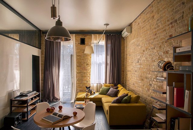 A living room with a brick wall and a yellow couch.