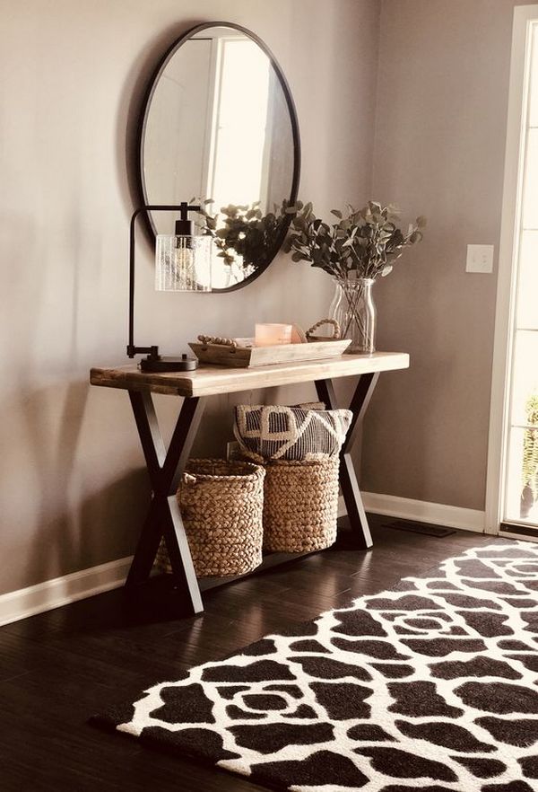 An entryway with a black and white rug and a mirror.