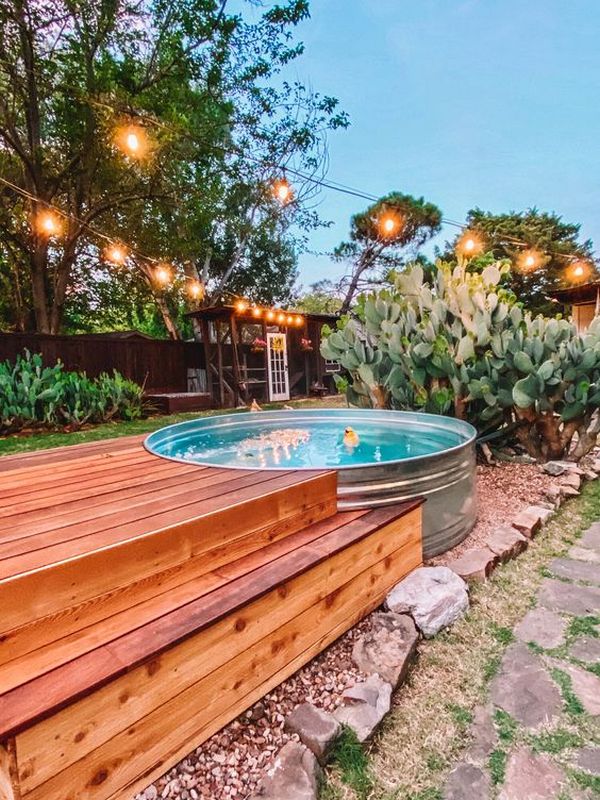 A backyard with a wooden deck and a pool.