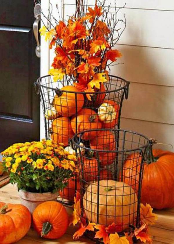 A basket full of pumpkins and leaves on a porch.