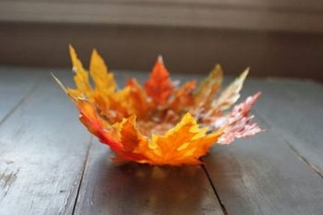 A bowl made out of leaves sitting on a wooden table.