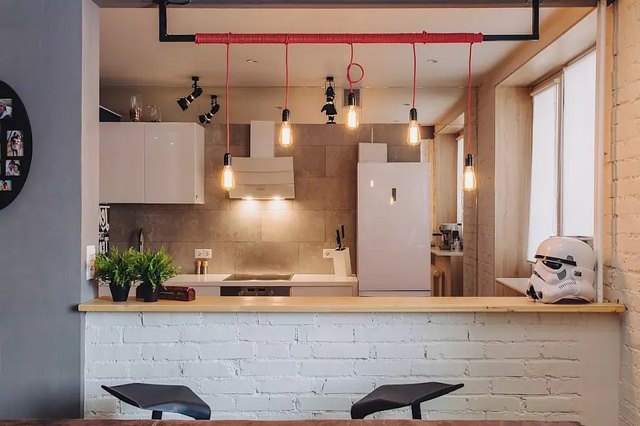 A kitchen with red pendant lights and a wooden table.