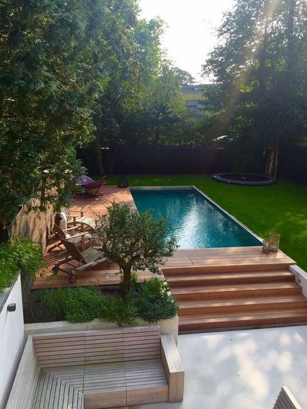 A modern backyard with a wooden deck and a swimming pool.