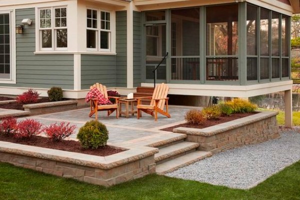 A small backyard with a patio and a screened in porch.