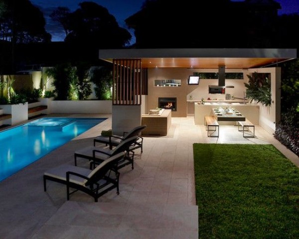 A modern backyard with a swimming pool and outdoor kitchen.
