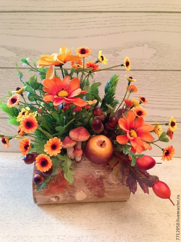 An arrangement of orange flowers and berries on a wooden log.