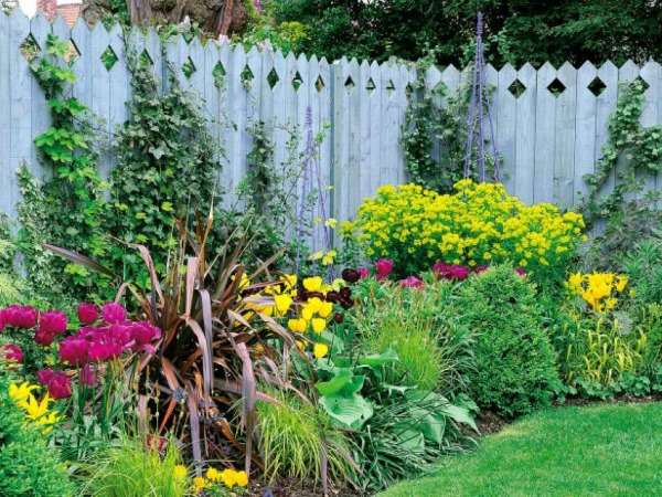 A garden with a fence and colorful flowers.