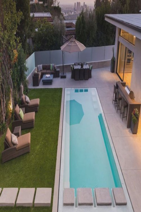 A modern backyard with a swimming pool and lounge chairs.