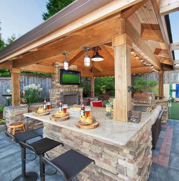 An outdoor kitchen with a fireplace and bar stools.