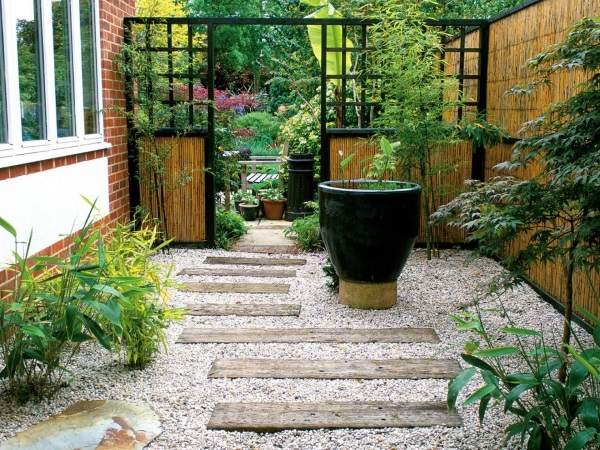 A small garden with a gravel path and potted plants.