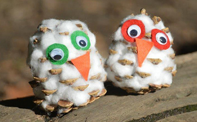 Two owls made out of pine cones.