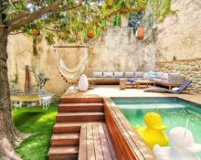 A backyard with a swimming pool and a wooden deck.
