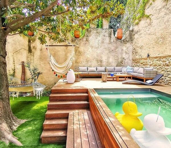 A backyard with a swimming pool and a wooden deck.