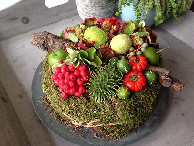 A cake decorated with moss and fruits.