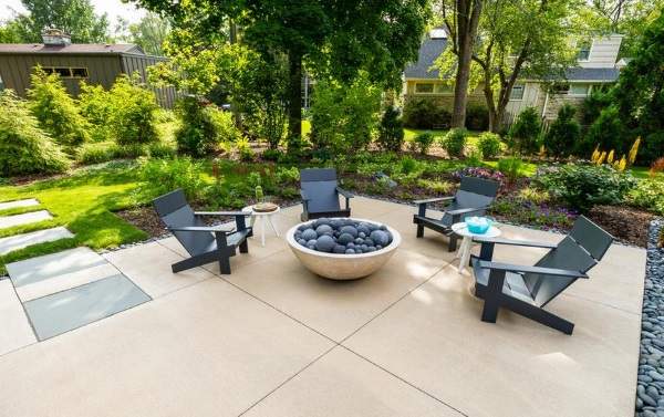 A backyard with a fire pit and chairs.