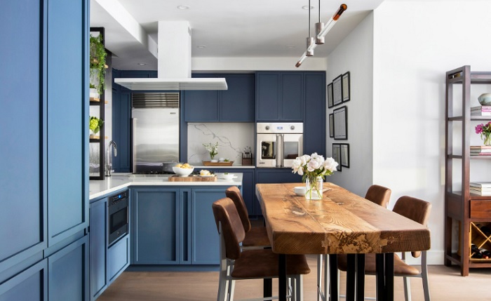 A kitchen with blue cabinets and a wooden table.