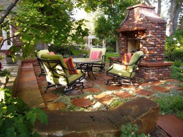 A backyard with a brick fireplace and patio furniture.