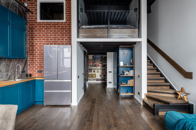 A kitchen with blue cabinets and a staircase.