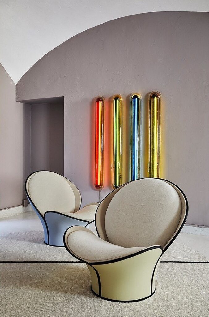 Two colorful chairs in a room with a colorful wall.