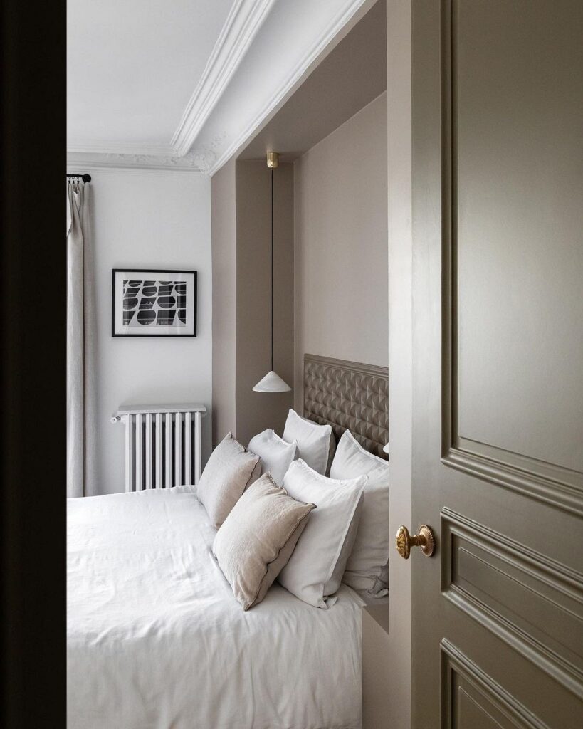 A bedroom with a white bed and grey walls.