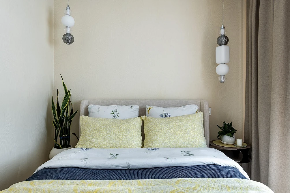 A bed with a yellow and white comforter and a plant.