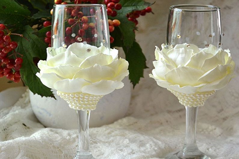 Two champagne flutes with white flowers on them.