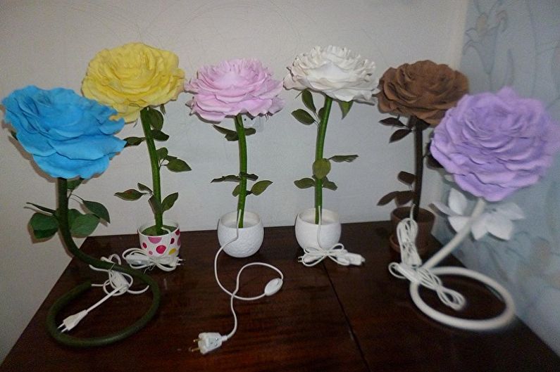 Four different colored roses in a vase on a table.