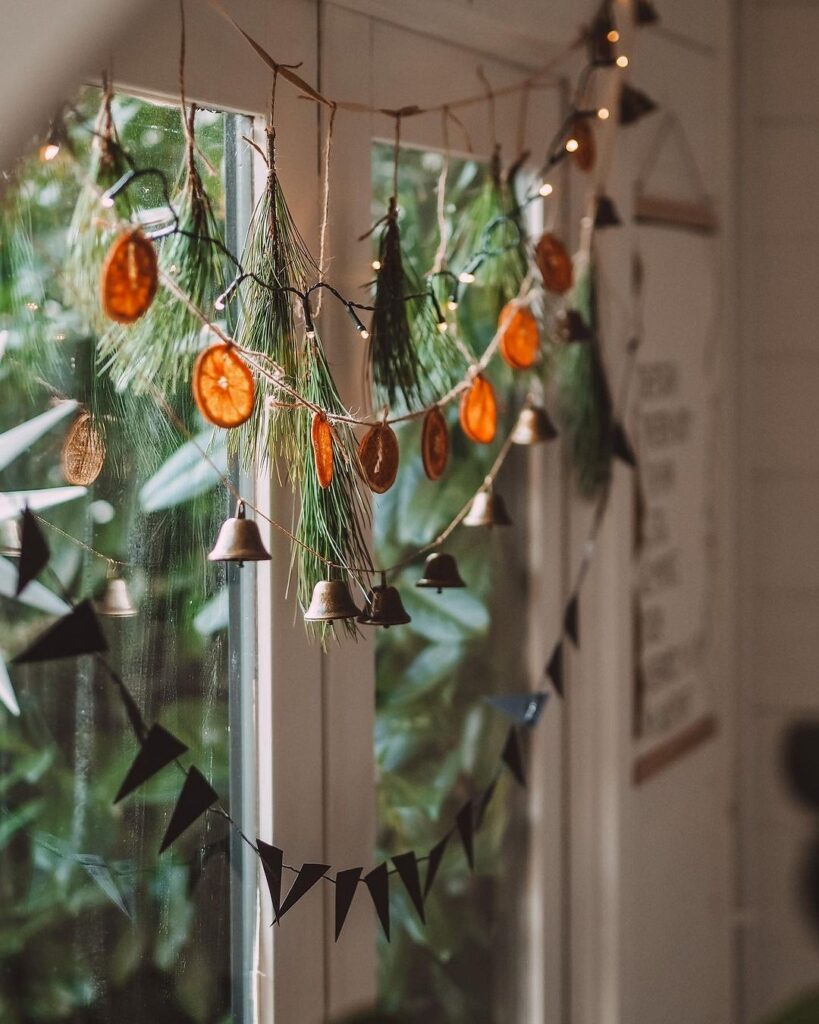 A christmas garland hangs on a window sill.