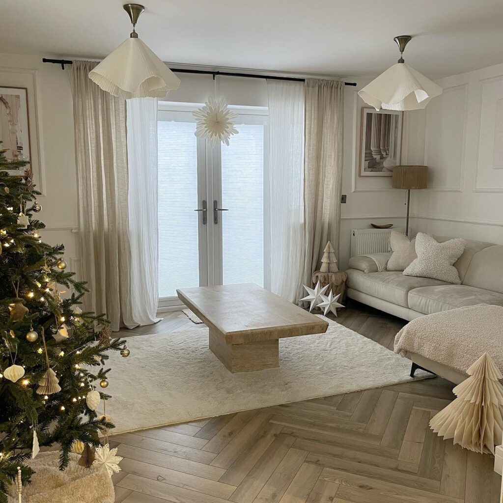 A living room with a christmas tree and white decorations.