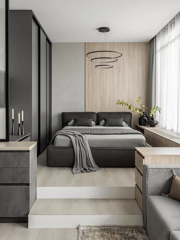 A modern bedroom with grey walls and wooden floors.