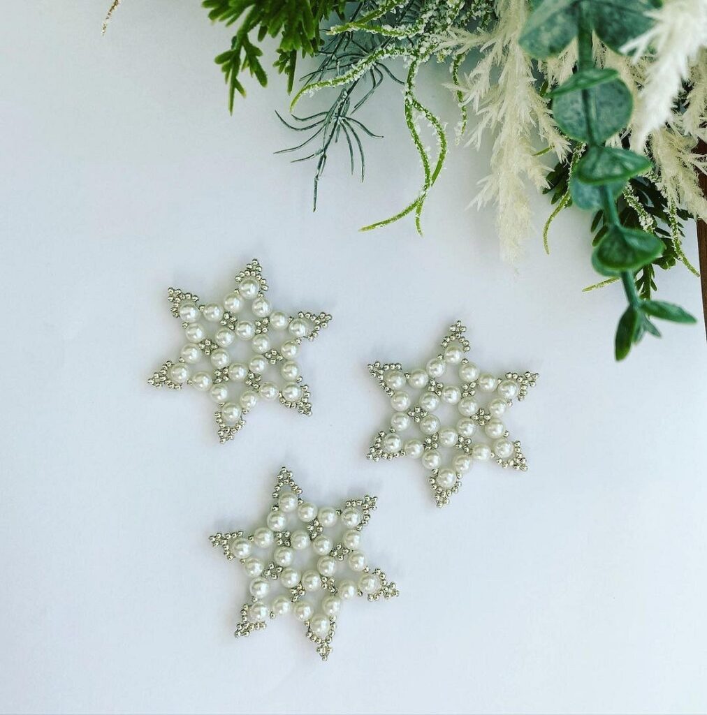 Three snowflake ornaments on a white table.