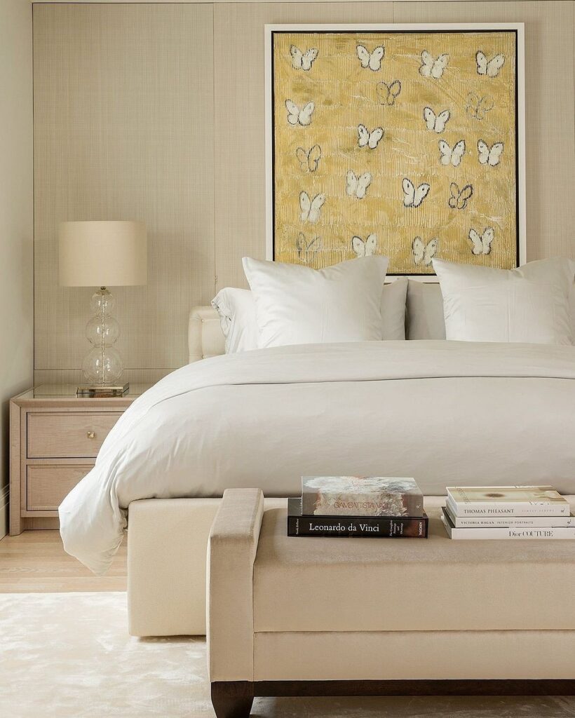 A bedroom with a white bed and a butterfly print on the wall.