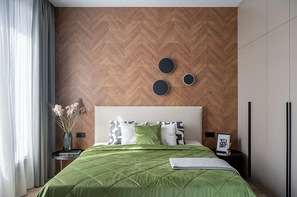 A bedroom with a green comforter and wooden walls.