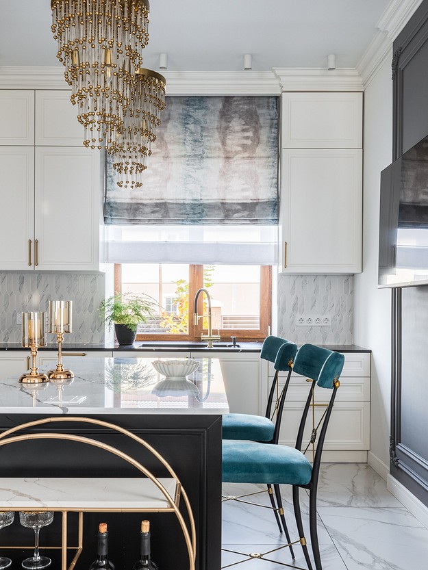 A black and gold kitchen with blue chairs and a chandelier.