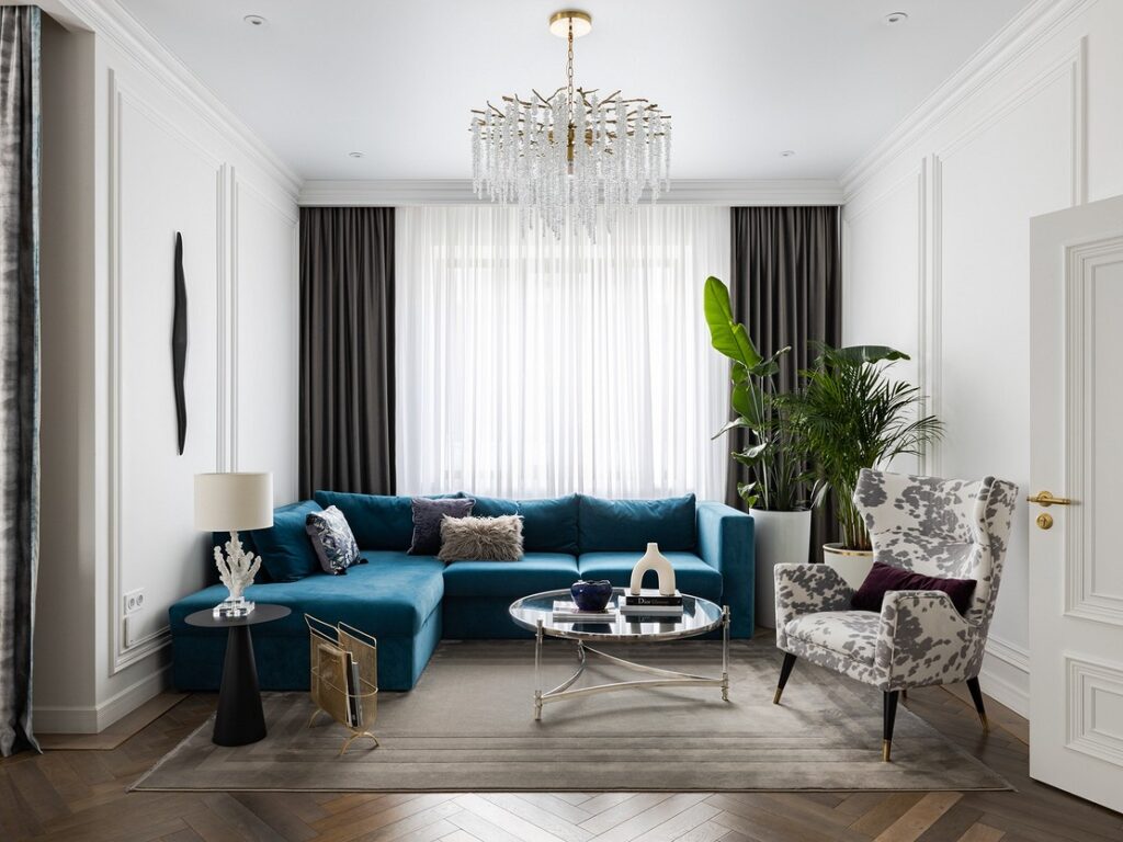 A living room with a blue couch and a chandelier.