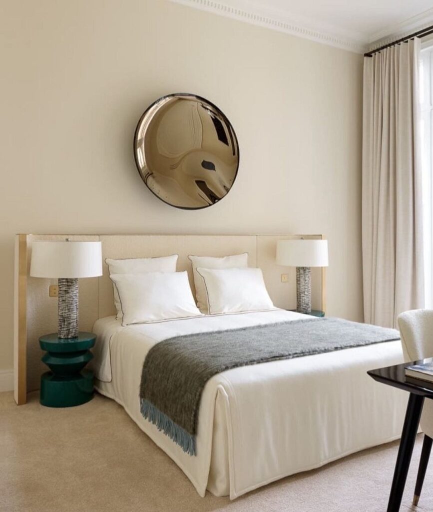 A beige bedroom with a large mirror above the bed.