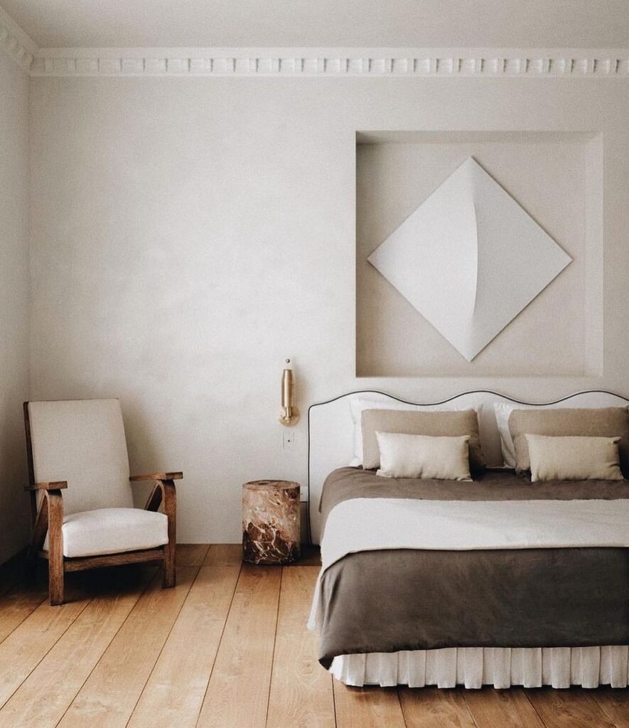 A bedroom with white walls and wooden floors.