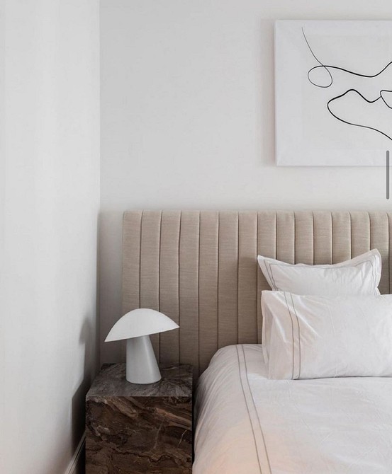 A bedroom with a white bed and a wooden bedside table.