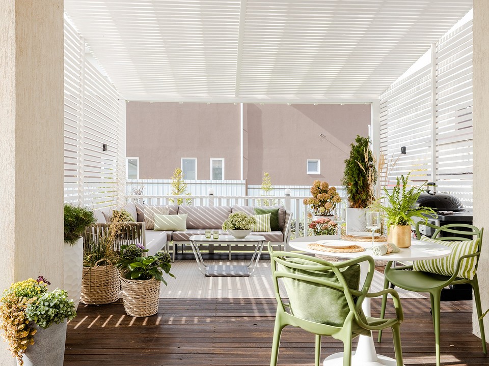 A balcony with green furniture and a table and chairs.