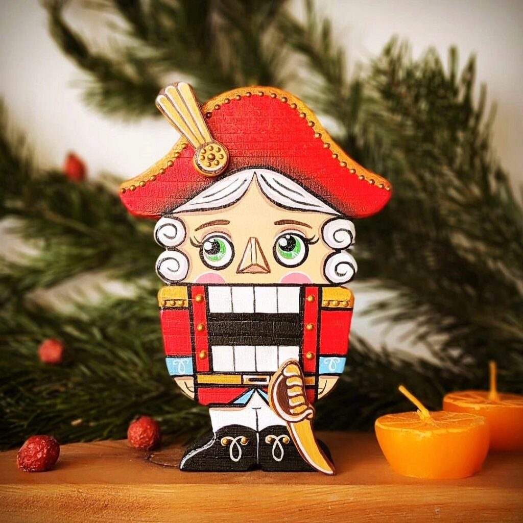 A wooden nutcracker sitting on a table next to a christmas tree.