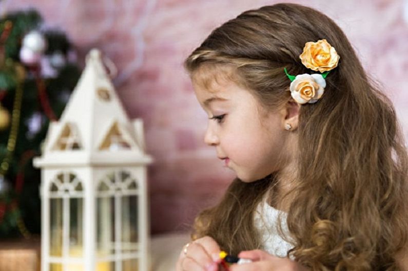 A little girl is sitting in front of a christmas tree.