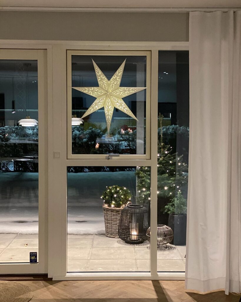 A christmas star hanging from a window in a living room.