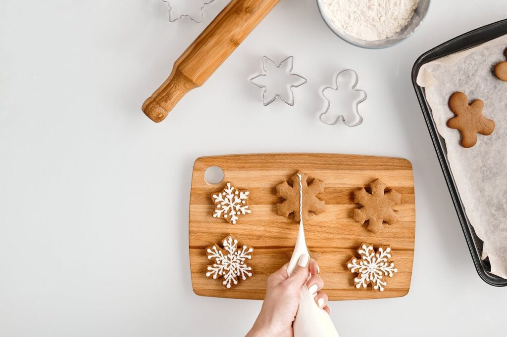 A person is making gingerbread cookies on a cutting board.