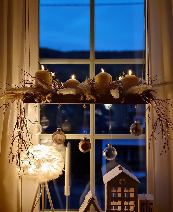 A christmas window display with candles and ornaments.