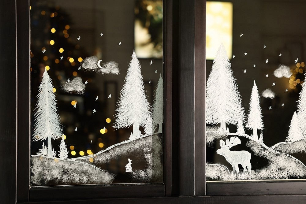 A window with a snow scene and deer.