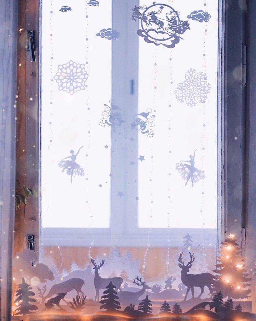 A window in a room with a christmas tree and snowflakes.