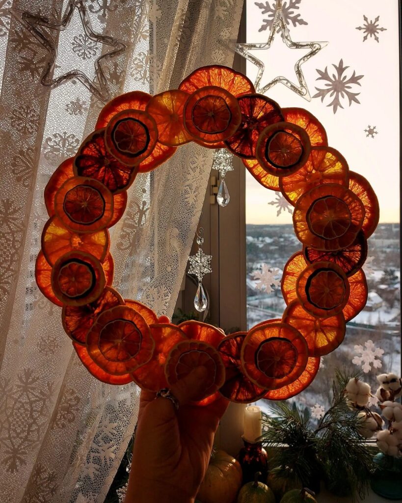 A person is holding a wreath made of orange slices.