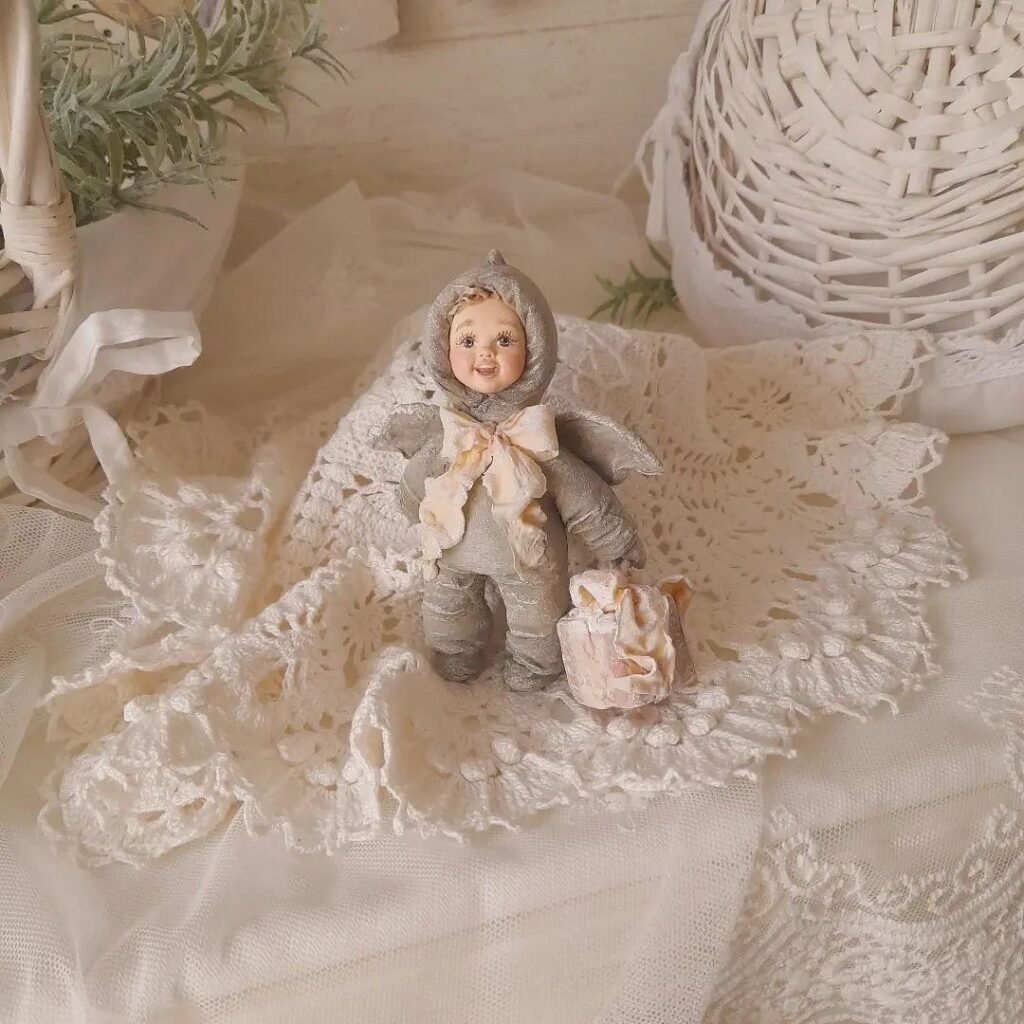 A small doll is sitting on a white tablecloth.