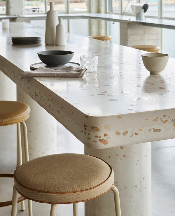 A dining table with stools and a bowl of food.