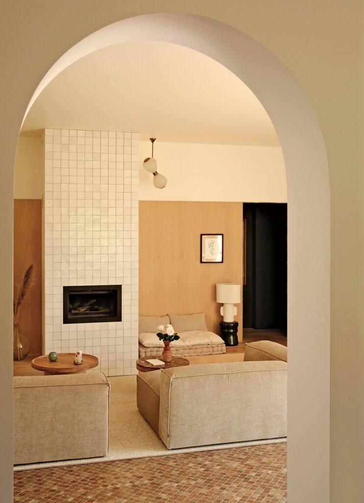 An archway leads into a living room with couches and a fireplace.